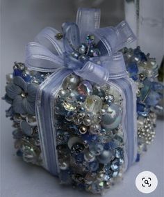 a blue bouquet with pearls and bows on it sitting next to a vase filled with flowers