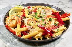 a plate of pasta with shrimp, peppers and parmesan cheese on the side