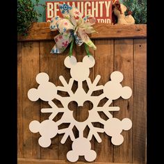 a snowflake hanging on the side of a wooden wall with mickey mouse decorations