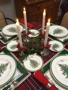 a christmas table setting with candles, plates and napkins on top of the table