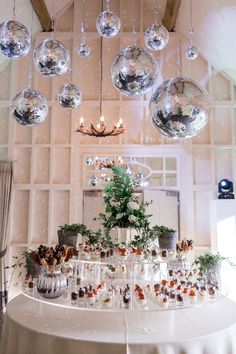 a table topped with lots of wine glasses and christmas ornaments hanging from the ceiling above it