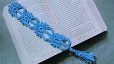 an open book with a crocheted tassel on top of it, sitting on a table