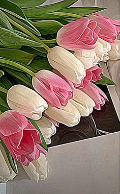 pink and white tulips are in a vase on a table with green leaves