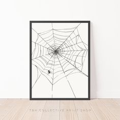 a spider web is hanging on the wall next to a wooden floor with a black frame