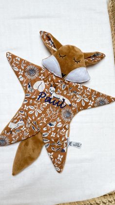 a brown and white stuffed animal laying on top of a bed next to a pillow