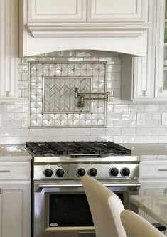 a stove top oven sitting inside of a kitchen next to white cabinets and counter tops