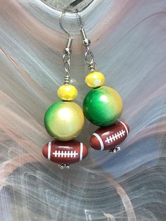 Green and gold beaded earrings with football.  Green Bay packers!  football bead and large bead is plastic.  yellow  of bead is  glass. 2 inches long.  silver ear wires. Gold Beaded Earrings, Gold Football, Football Earrings, Green Bay Packers Football, Gold Bead Earrings, Packers Football, Green Bay Packers, Green Bay, Earrings Silver