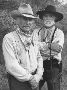 two men in cowboy hats standing next to each other with their arms around one another