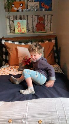 a young boy sitting on top of a bed