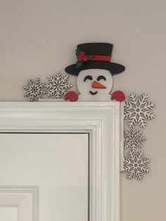 a snowman with a top hat and nose is on the wall next to a mirror