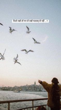 a man standing next to a body of water with seagulls flying above him