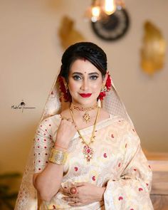 a woman in a white and red sari with jewelry on her neck posing for the camera