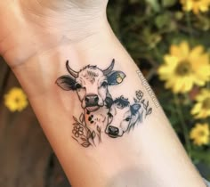 a small cow tattoo on the wrist with flowers around it's neck and head