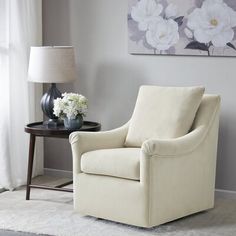 a living room with white furniture and flowers on the table in front of the window