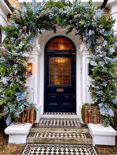 the front door is decorated with greenery and potted plants on either side of it