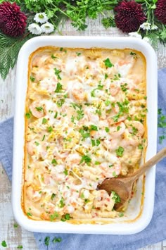 a casserole dish with shrimp, cheese and parsley in it on a blue towel