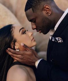 a man in a suit kissing a woman's face with her eyes close together