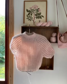 a pink sweater hanging from a wooden shelf