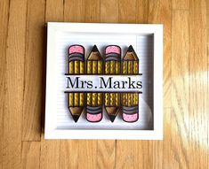 a white box with some crayons in it on a wooden floor and the words mrs marks