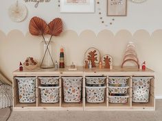 a shelf with baskets and toys on it in front of a wall decorated with seashells