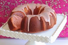 a bundt cake sitting on top of a white cake plate next to a pink wall