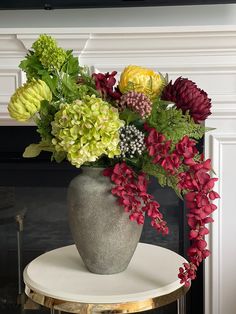 a vase filled with flowers sitting on top of a table next to a fire place