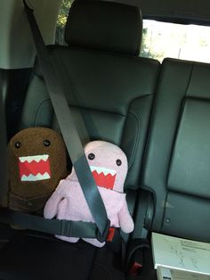 two stuffed animals sitting in the back seat of a car, one with teeth on it