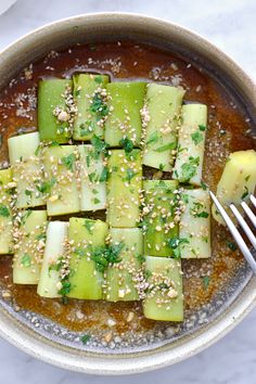 a bowl filled with sliced cucumbers and topped with sesame seeds