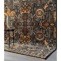 an intricately designed tapestry hanging on the wall in front of a chair and table