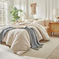 a bedroom with white walls and beige bedding