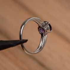 It is a natural amethyst ring. The main stone is 7mm*7mm round cut, weight about 1.25 carats. The basic metal is sterling silver and plated with rhodium. To change the metal to a solid gold (white/rose) or platinum is also available, please ask for a quotation if you want. You can also go to my shop Home for more elegant rings: https://www.etsy.com/shop/godjewelry?ref=hdr_shop_menu More amethyst rings: https://www.etsy.com/shop/godjewelry?ref=seller-platform-mcnav&section_id=20709248 Customi Elegant Purple Solitaire Birthstone Ring, Classic Amethyst Cubic Zirconia Promise Ring, Elegant Purple Birthstone Ring, Classic Amethyst Round Cut Birthstone Ring, Classic Amethyst Birthstone Ring With Round Cut, Amethyst Birthstone Ring With Center Stone In White Gold, Elegant Amethyst Birthstone Ring With Round Stone, White Gold Amethyst Birthstone Ring With Center Stone, Promise Ring With Tension Setting