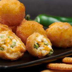 some food is on a black plate next to crackers and green pepper wedges