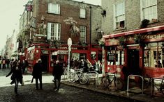 people are walking down the street in front of some buildings and bicycles parked on the sidewalk