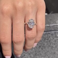 a woman's hand with a diamond ring on top of her finger and an engagement band