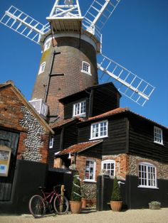 an old windmill sits next to a building with a bicycle parked in front of it