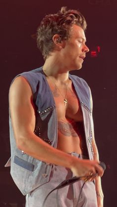 a man with no shirt on holding a microphone in his right hand and looking off to the side