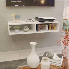 a table with vases and books on it in front of a flat screen tv