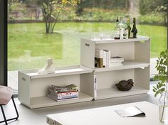 a white shelf sitting next to a window filled with bottles and glasses on top of it