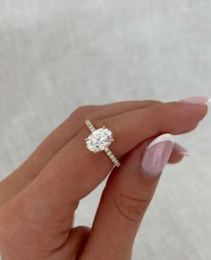 a woman's hand holding an engagement ring with a diamond on the middle and side