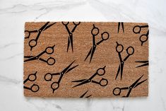 a door mat with scissors and hair clips on it next to a marble counter top