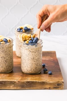 two jars filled with oatmeal and blueberries on top of a cutting board