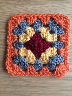 a crocheted square with an orange and blue center