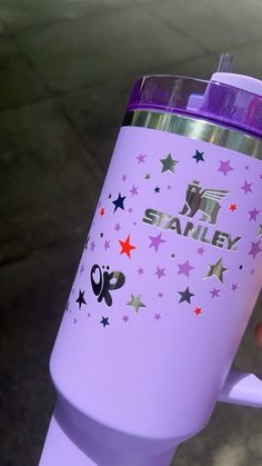 a person holding up a purple and silver starbucks cup with stars on it's side