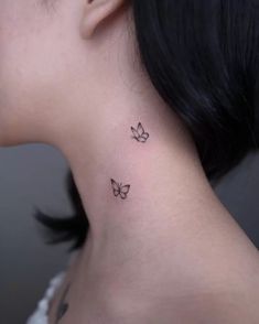 a woman's neck with two small butterflies on the back of her left ear