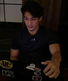 a man sitting in front of a laptop computer with stickers on it's screen