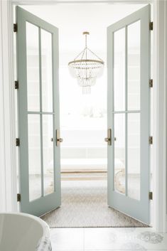 an open door leading to a bathroom with a chandelier hanging from the ceiling