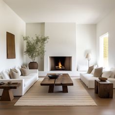 a living room filled with white furniture and a fire place in the middle of it