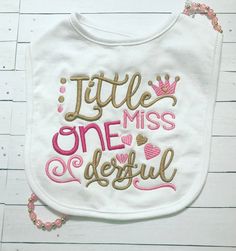 a bib with the words little miss, one beautiful on it and a crown