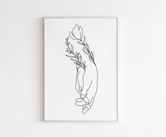 a black and white drawing of a hand holding a flower on a white wall above it