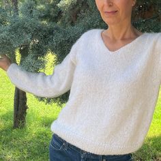 a woman standing in front of trees with her arms out and looking at the camera